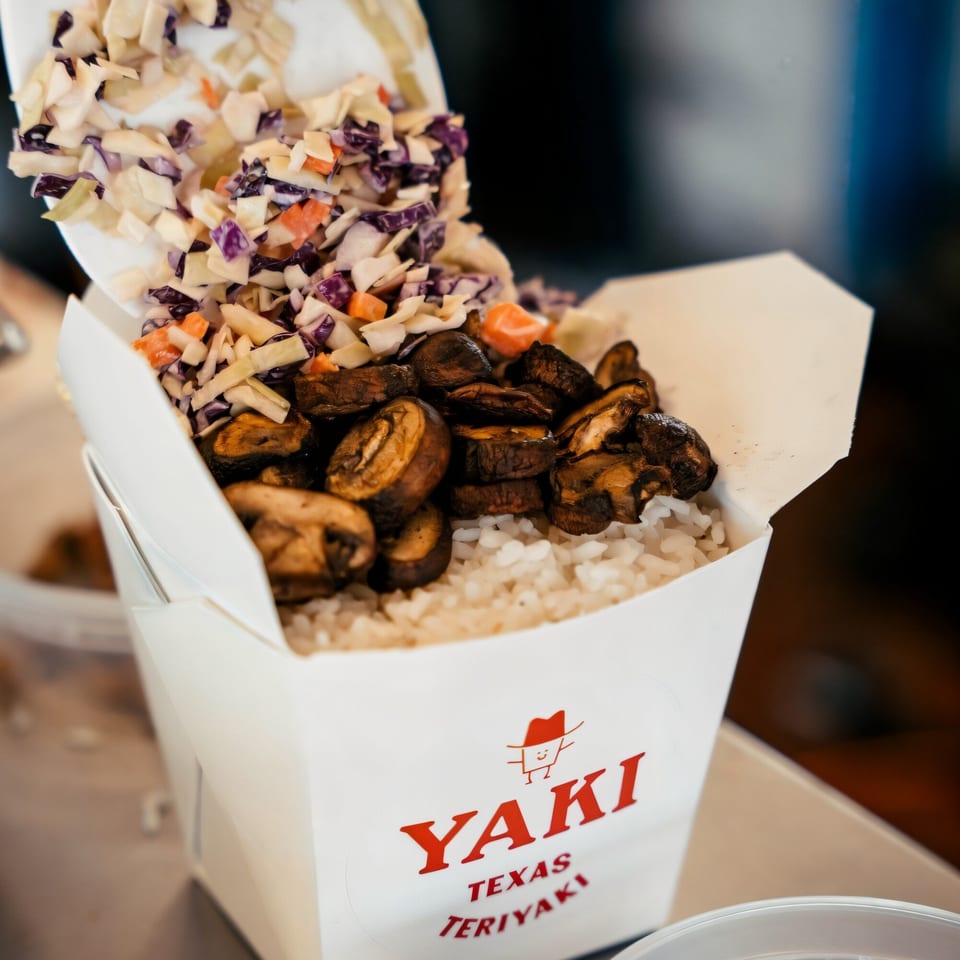 Yaki Texas Teriyaki takeout box filled with rice, mushrooms, and colorful coleslaw.